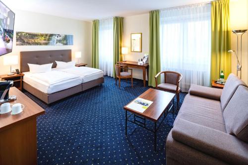 a hotel room with a bed and a couch at AHORN Seehotel Templin in Templin
