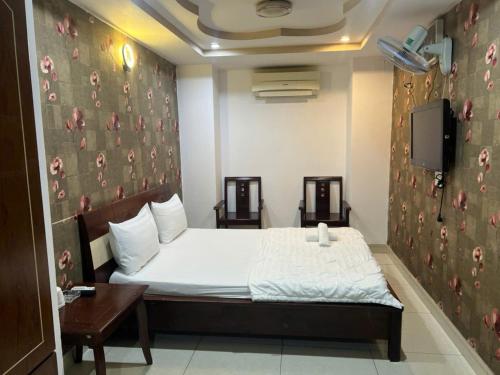 a bedroom with a bed and a tv on a wall at Quang Huy Hotel in Ho Chi Minh City