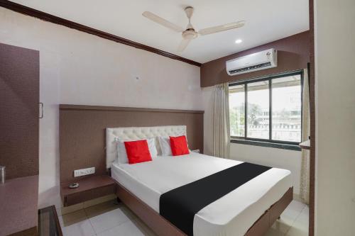 a bedroom with a bed with red pillows and a window at Collection O Sapna in Mire