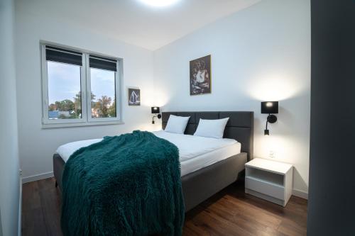 a bedroom with a bed with a green blanket on it at NWK Apartments & SPA in Lidzbark