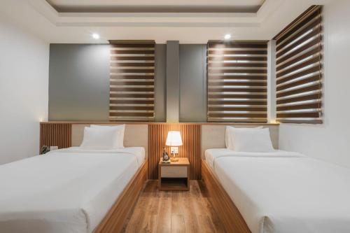 two twin beds in a room with windows at Nature Hotel - Nam Ky Khoi Nghia in Da Lat