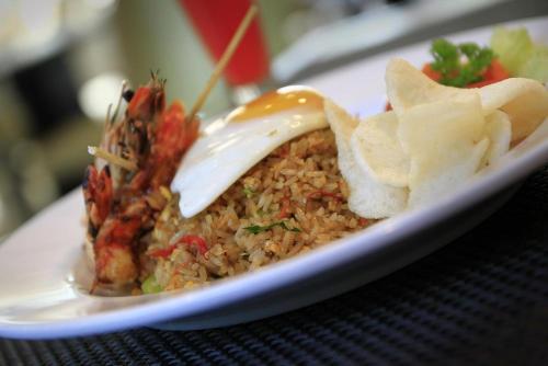 a plate of food with rice and chips on a table at Mars City Hotel in Denpasar