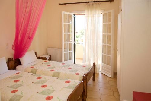 a bedroom with two beds and a large window at Katerina Pool Apartments in Acharavi
