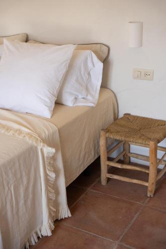 a bed with white pillows and a table next to it at Finca Luca Oliva in Zahara de la Sierra