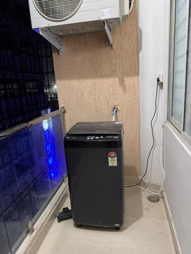 a trash can sitting next to a wall with a fan at Nest Quest in Haidar Sāhibgūda