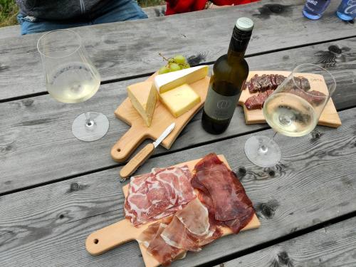 a table with cheese and meats and a bottle of wine at Ustreia Orta in Lohn