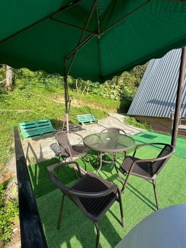 a table and chairs under a green umbrella at Eco cottage sunrise merisi in Merisi