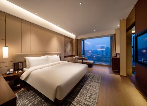 a bedroom with a large white bed and a large window at Maison New Century Hotel Cixi Hangzhou Bay in Cixi