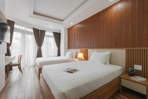 a hotel room with two beds and a television at Nature Hotel - Nam Ky Khoi Nghia in Da Lat