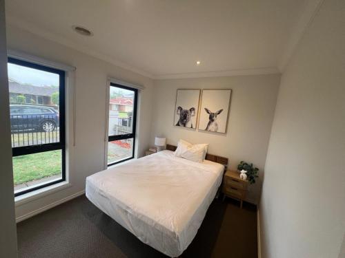 a bedroom with a bed and two windows at The Lakes Homestead - Shared House in Mill Park