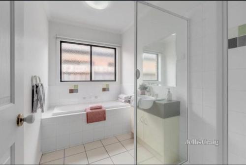 a white bathroom with a tub and a sink at The Lakes Homestead - Shared House in Mill Park