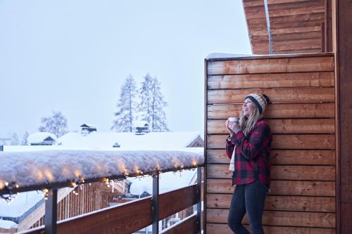 une femme debout à côté d'un bâtiment en bois dans la neige dans l'établissement Chalet Rytola, modern & central chalet in Chamonix, à Chamonix-Mont-Blanc