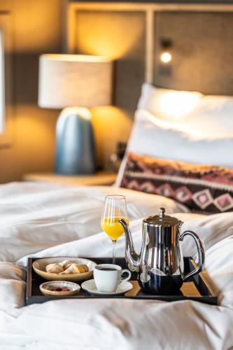 a tray of food and a glass of wine on a bed at Henningsvær Bryggehotell - by Classic Norway Hotels in Henningsvær