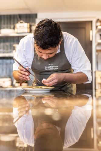 a man in a kitchen preparing food on a plate at Henningsvær Bryggehotell - by Classic Norway Hotels in Henningsvær