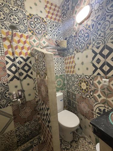 a bathroom with a toilet and colorful wallpaper at Riad Sanwa in Marrakech