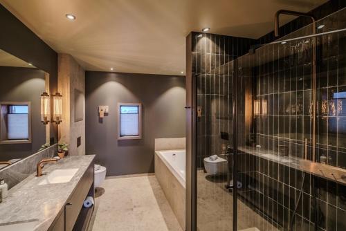 a bathroom with a shower and a sink and a tub at Henningsvær Bryggehotell - by Classic Norway Hotels in Henningsvær