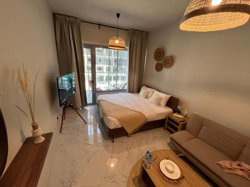 a bedroom with a bed and a couch and a tv at The Chic Retreat, Stylish Studio Close to Yas & Airport in Abu Dhabi