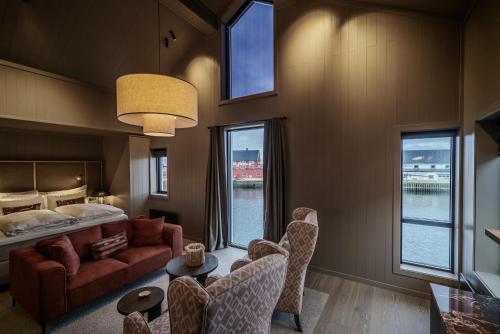 a living room with a bed and a couch and chairs at Henningsvær Bryggehotell - by Classic Norway Hotels in Henningsvær