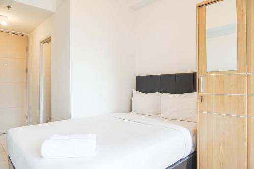 ein Schlafzimmer mit einem weißen Bett und einem Spiegel in der Unterkunft Comfortable and Well Design Studio Tokyo Riverside PIK 2 Apartment By Travelio in Rawalembang