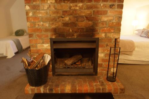 a brick fireplace with logs in it in a room at The Carriages Boutique Hotel and Vineyard in Pokolbin