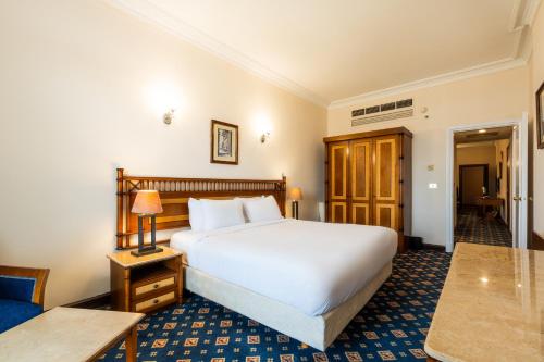 a bedroom with a large white bed and a table at Om Kolthoom Hotel in Cairo