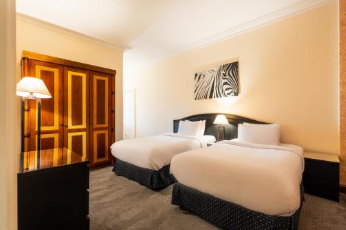 two beds in a hotel room with white sheets at Om Kolthoom Hotel in Cairo