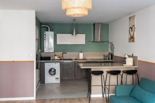 une cuisine avec des murs verts et un comptoir avec des tabourets dans l'établissement Le Cosy, spacieux et calme, à Lens