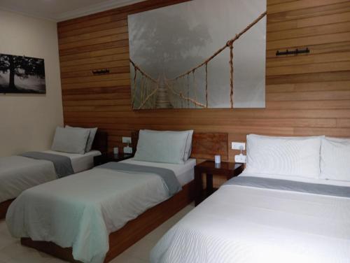 three beds in a room with a bridge on the wall at Naura Roomstay in Kuala Tahan