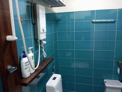 a blue tiled bathroom with a toilet and a mirror at Naura Roomstay in Kuala Tahan