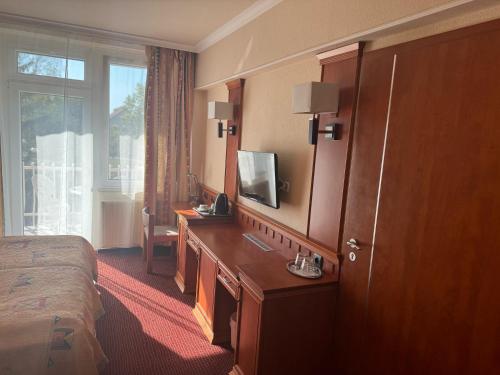 a hotel room with a bed and a desk with a television at Csipke Hotel in Kiskunhalas