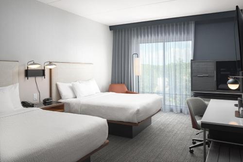 a hotel room with two beds and a desk at Courtyard by Marriott Nashville Smyrna in Smyrna