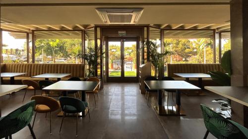 a restaurant with tables and chairs and windows at Hotel Boutique Mirasierra in Villacañas