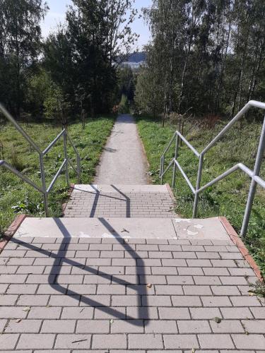 a brick path with a shadow of a fence at Apartament Laurka in Kamienna Góra