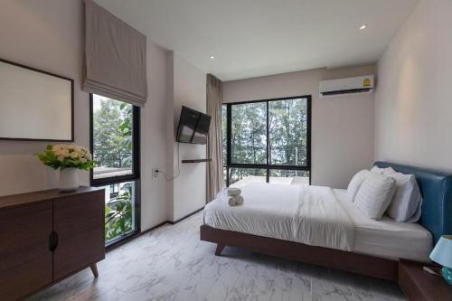 a bedroom with a large bed and large windows at The Title Beach Front in Rawai Beach