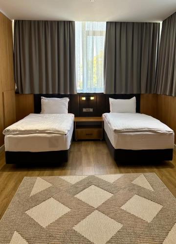 a room with two beds and a rug at WELLFORT HOTEL in Samarkand