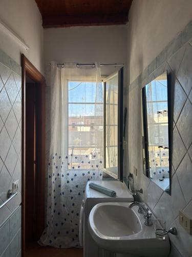 łazienka z umywalką, lustrem i oknem w obiekcie City Loft w mieście Marsala