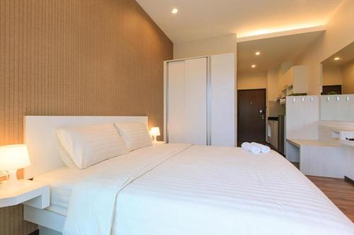 a bedroom with a large white bed and a kitchen at The Title Beach Front in Rawai Beach
