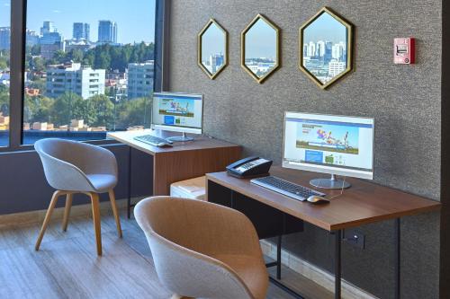 an office with two monitors and a desk with two chairs at City Express Plus by Marriott Ciudad de Mexico Interlomas in Mexico City
