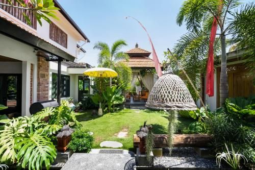 a garden with an umbrella and a house at The Kembali Luxury Villa - Melaka 5 Bedroom in Melaka