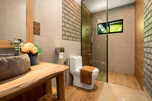 a bathroom with a toilet and a glass shower at The Kembali Luxury Villa - Melaka 5 Bedroom in Melaka