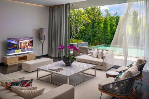 a living room with a couch and a table and a tv at Anantara Desaru Coast Resort & Villas in Desaru