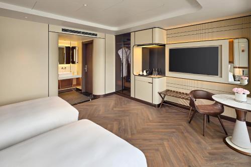 a hotel room with a bed and a table and a television at Grand Pioneers Halong Bay Cruise 1 in Ha Long