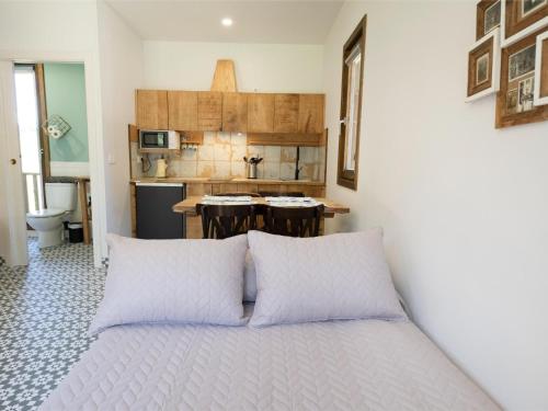 a bed with pillows in a room with a kitchen at Cabaña del Molinero in Palas de Rei