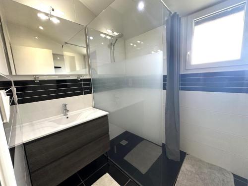 a bathroom with a sink and a shower with a mirror at La sauvagine in Soustons