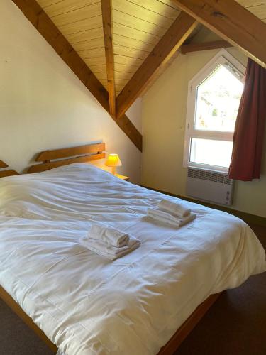 un grand lit blanc dans une chambre avec une fenêtre dans l'établissement VVF Fouesnant les Glénan, à Fouesnant