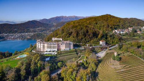 ein großes Gebäude auf einem Hügel neben einem See in der Unterkunft Resort Collina d'Oro - Hotel, Residence & Spa in Lugano
