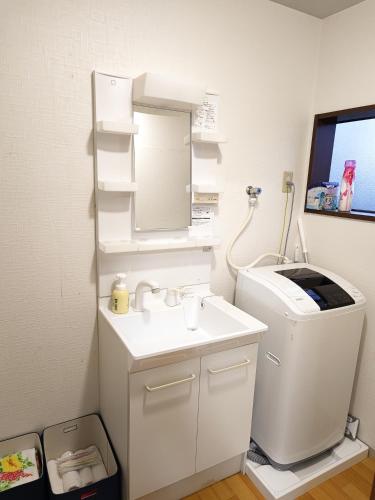 a bathroom with a sink and a mirror at Rent a leaping floor villa 2 mins to station in Sakai