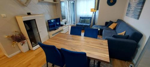 a living room with a wooden table and blue chairs at OPERA LUX APARTMENTS - Green Hill kompleks Sokobanja & Free Parking - kod Akva Parka in Soko Banja