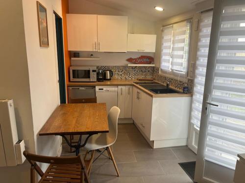 une cuisine avec des placards blancs et une table en bois avec des chaises dans l'établissement Location Vendée Globe La Chaume, à Les Sables-dʼOlonne
