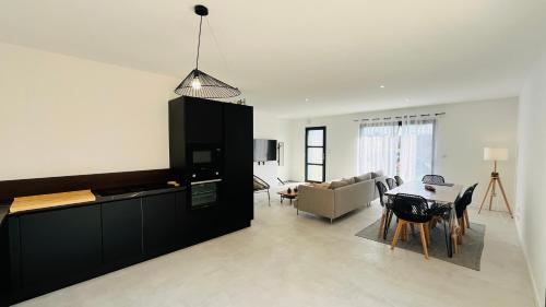 une cuisine et un salon avec une table et un canapé dans l'établissement La Tonka, maison neuve proche océan, à Saint-Jean-de-Monts
